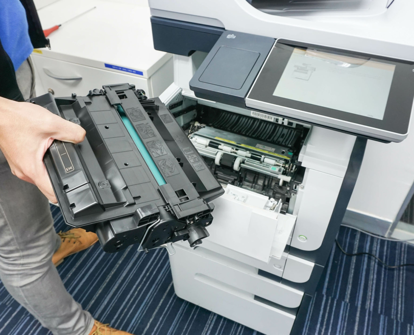Person pulling out toner cartridge from printer