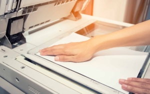 woman hands putting a sheet of paper into a copying device