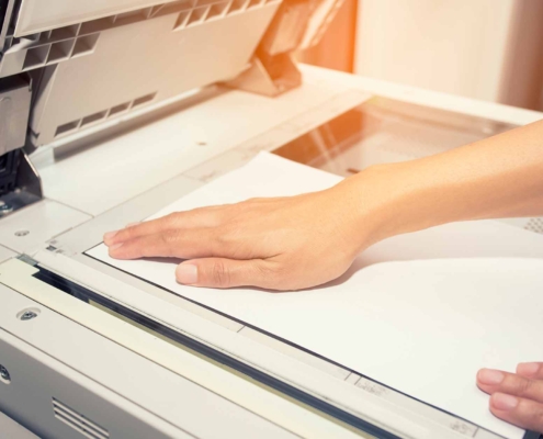 woman hands putting a sheet of paper into a copying device