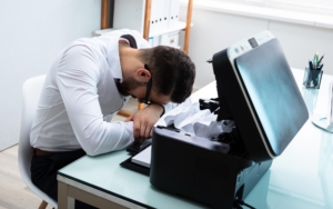Image of a frustrated person trying to fix a printer.