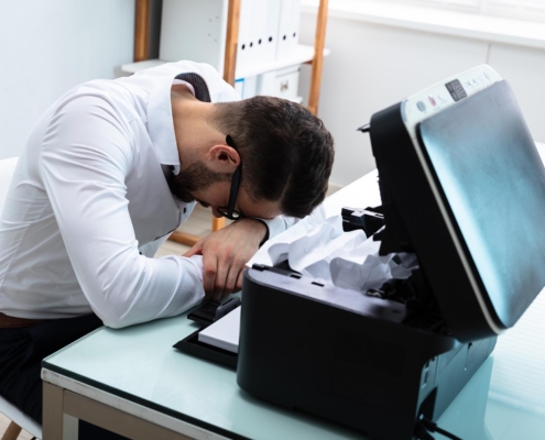 Image of a frustrated person trying to fix a printer.