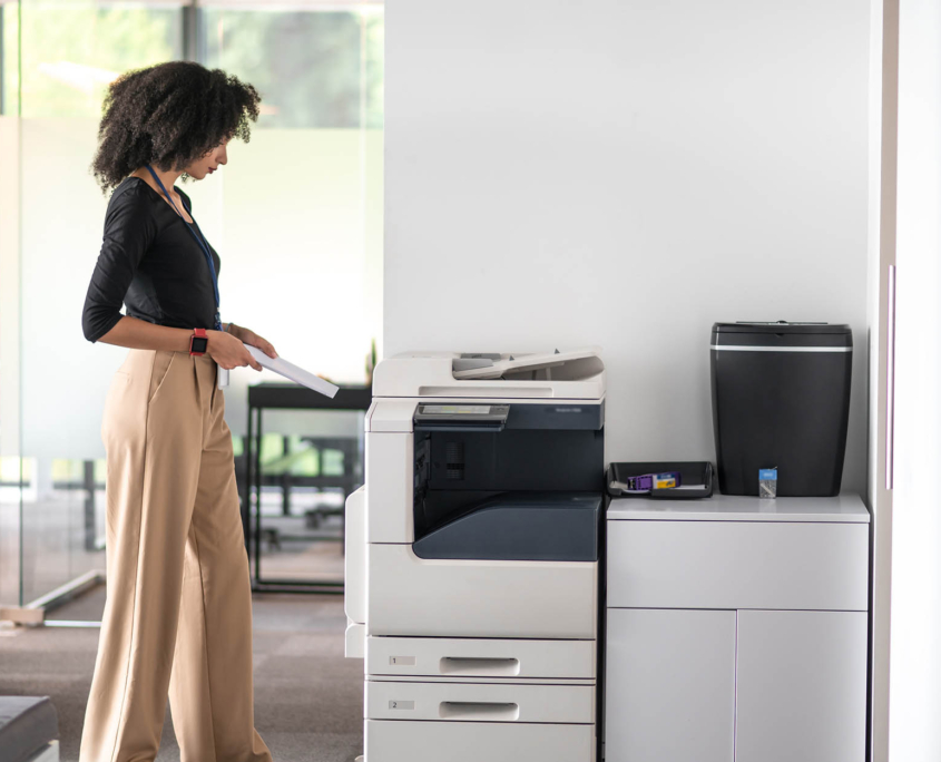 Worker standing next to printer waiting for documents