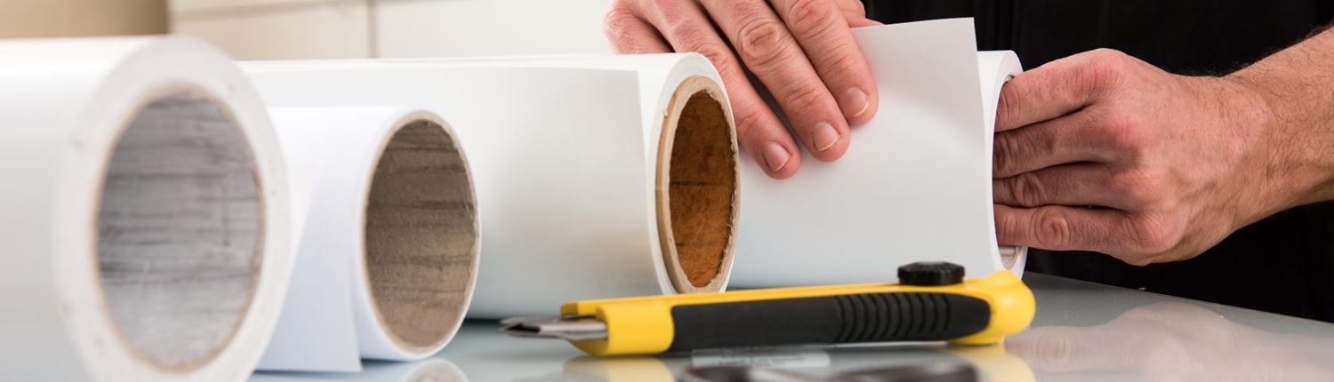 Close-up of a print specialist rolling up large bolts of paper